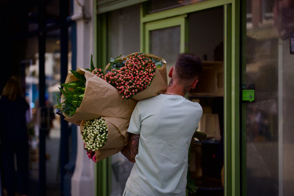 A man holding a large bouquet of fresh flowers outside a flower shop near Waterloo Station Lambeth SE1. The bouquet features pinkish-red small berries, white berries, and lush green foliage, all wrapp